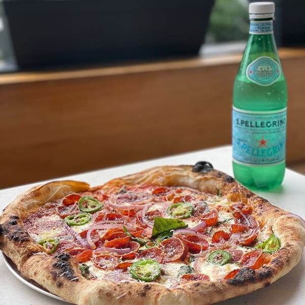 Rodrigo's Craft Pizza with pepperoni, red onion, jalapeños, and basil, next to a bottle of S.Pellegrino.