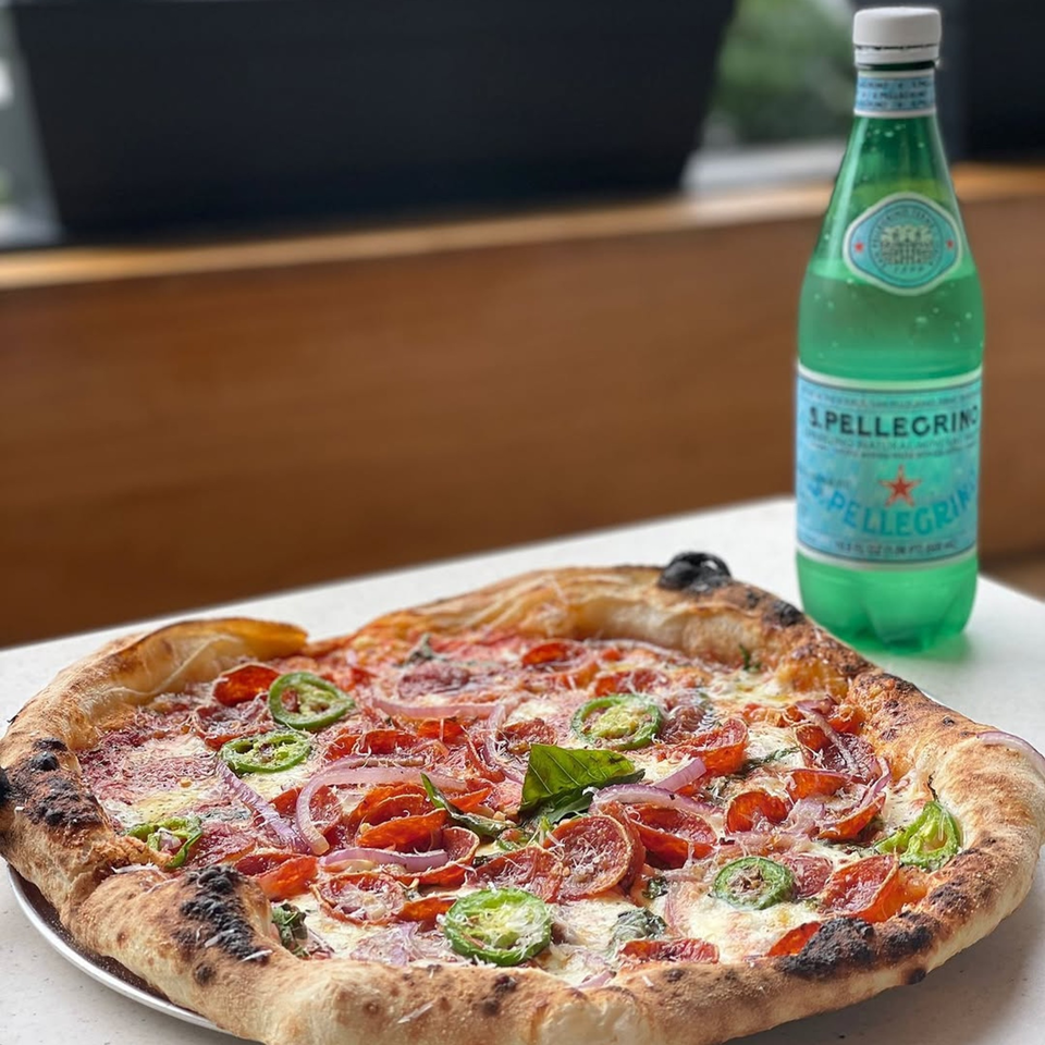 Rodrigo's Craft Pizza with pepperoni, red onion, jalapeños, and basil, next to a bottle of S.Pellegrino.