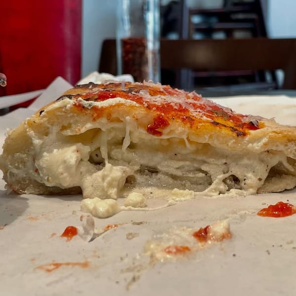 Close-up of a calzone slice from Rodrigo's Craft Pizza, revealing a creamy ricotta filling and sauce.