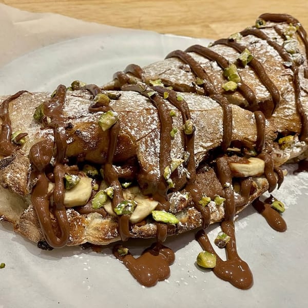 A dessert calzone from Rodrigo's Craft Pizza, drizzled with chocolate, powdered sugar, bananas, and pistachios.
